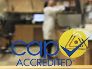 looking through glass wall at out-of-focus person doing research. Overlaid with CAP certified
